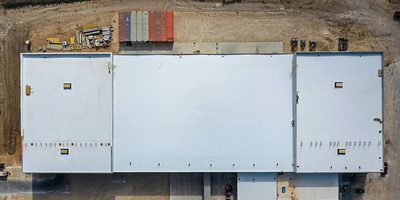 A white single-ply membrane roof on a large commercial building, from above
