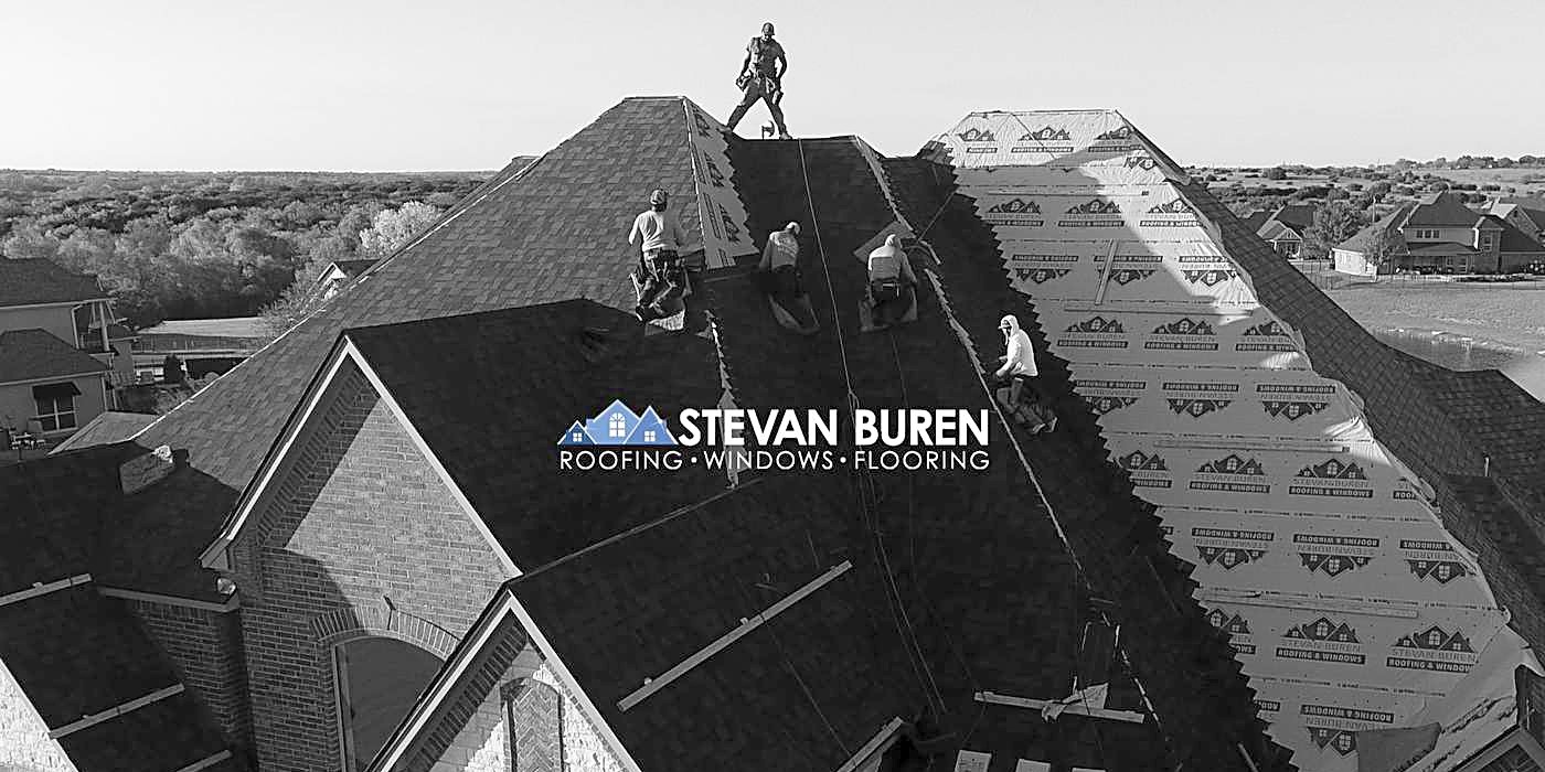 Black and white photo of roofers working on a steep residential roof