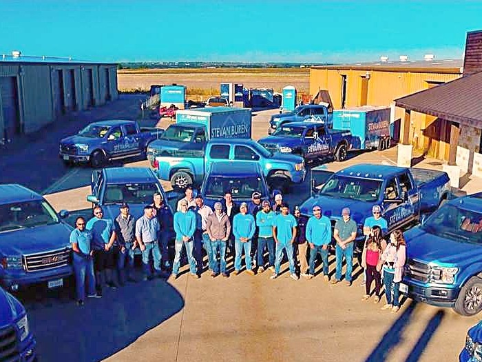 The Stevan Buren team lined up with their blue company trucks outside the Cleburne office