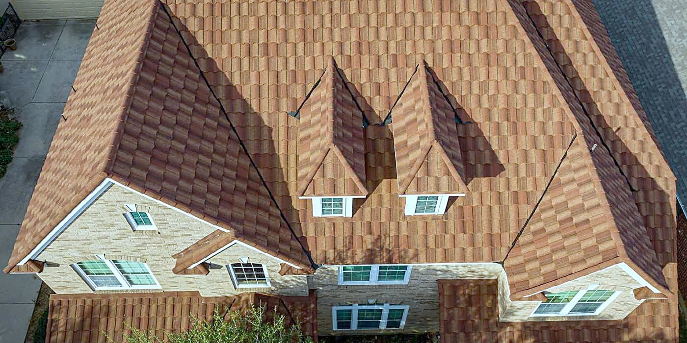 Dormers and valleys on a steep terracotta-colored shingle roof