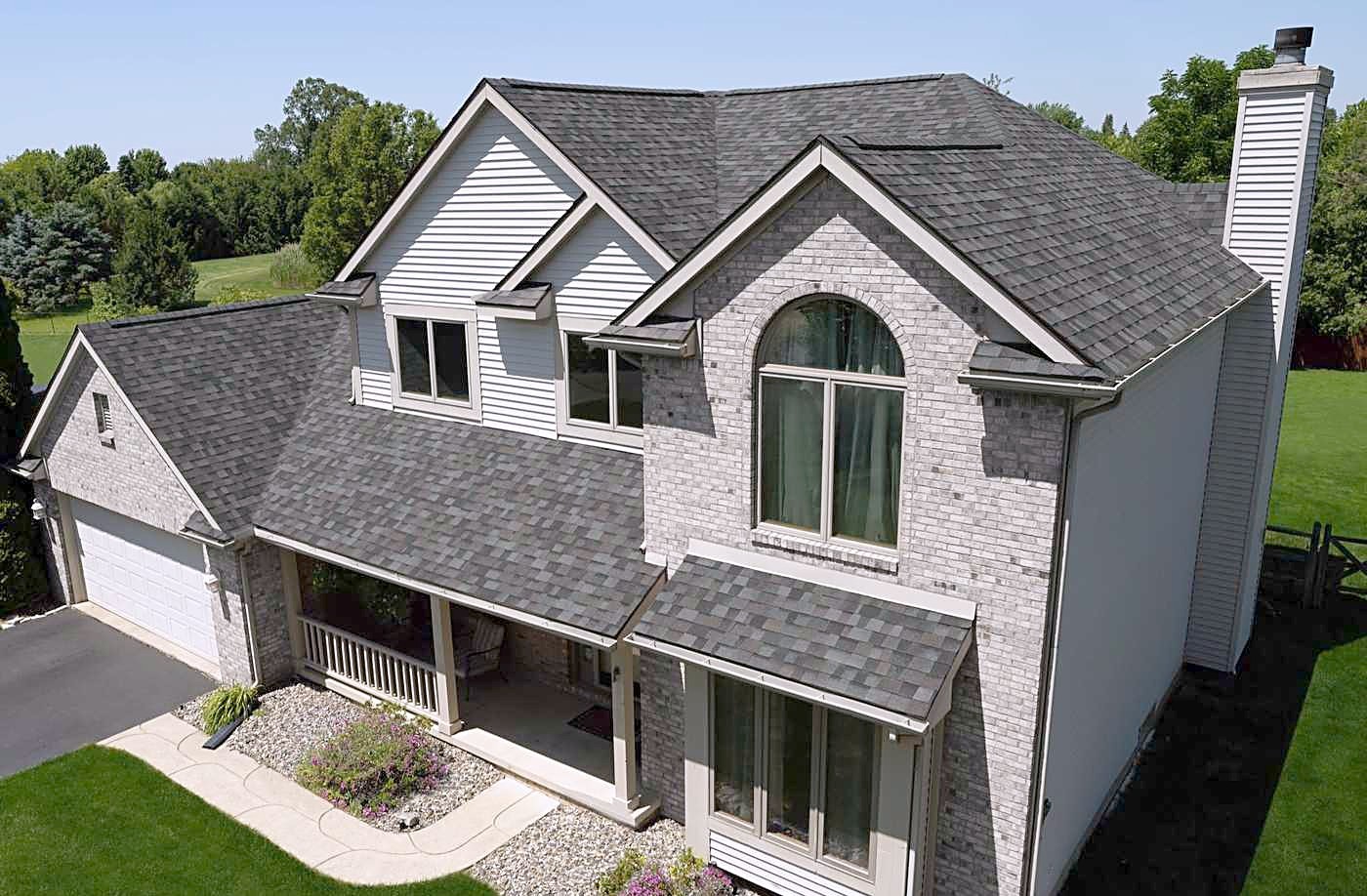 A two-story brick home with a new charcoal shingle roof
