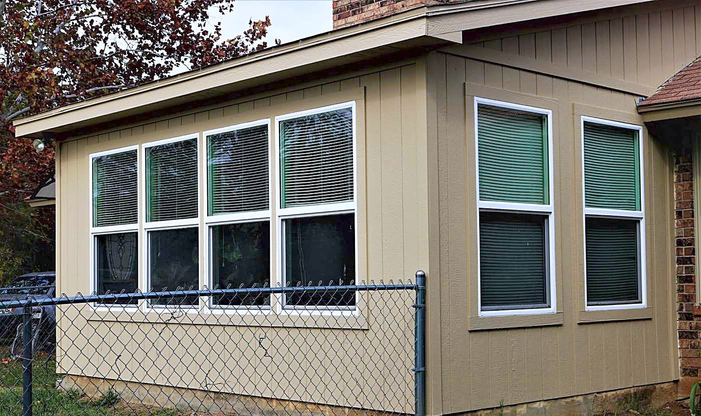 A tan sunroom addition with new white-framed windows
